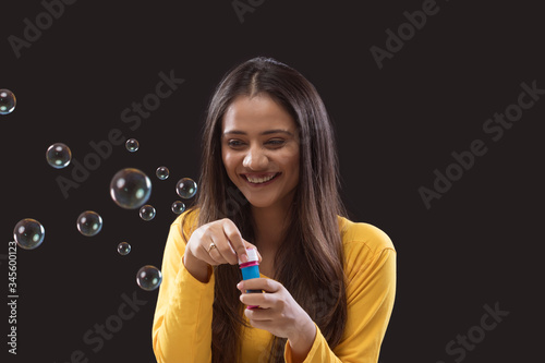 Young woman blowing soap bubbles Against Black Background 