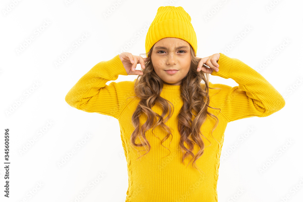 European attractive girl in a yellow hat closed her ears on a white background European attractive girl in a yellow hat closed her ears on a white background