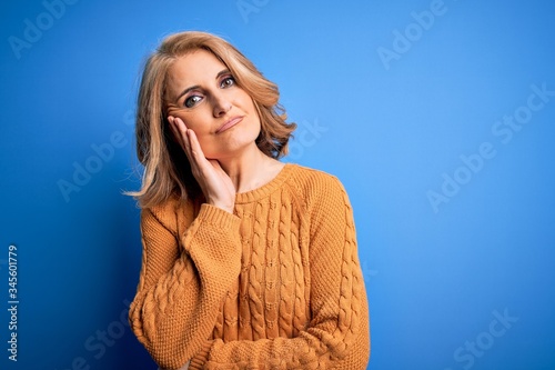Middle age beautiful blonde woman wearing casual sweater over yellow background thinking looking tired and bored with depression problems with crossed arms.
