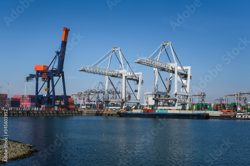 Huge cranes and ships anchored at harbor. International commercial port  city of Rotterdam background. Logistics business