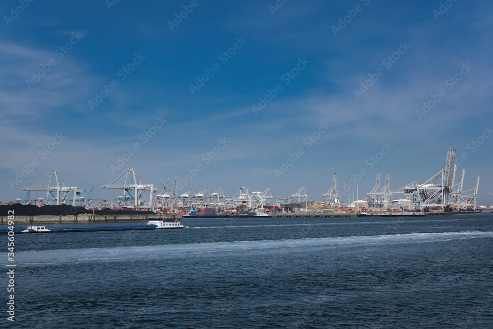 Huge cranes and ships anchored at harbor. International commercial port, city of Rotterdam background. Logistics business Huge cranes and ships anchored at harbor. International commercial port, city of Rotterdam background. Logistics business