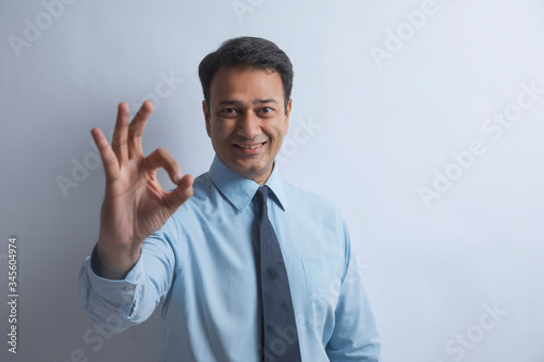 Smiling businessman in formal clothes making a hand gesture expressing good 