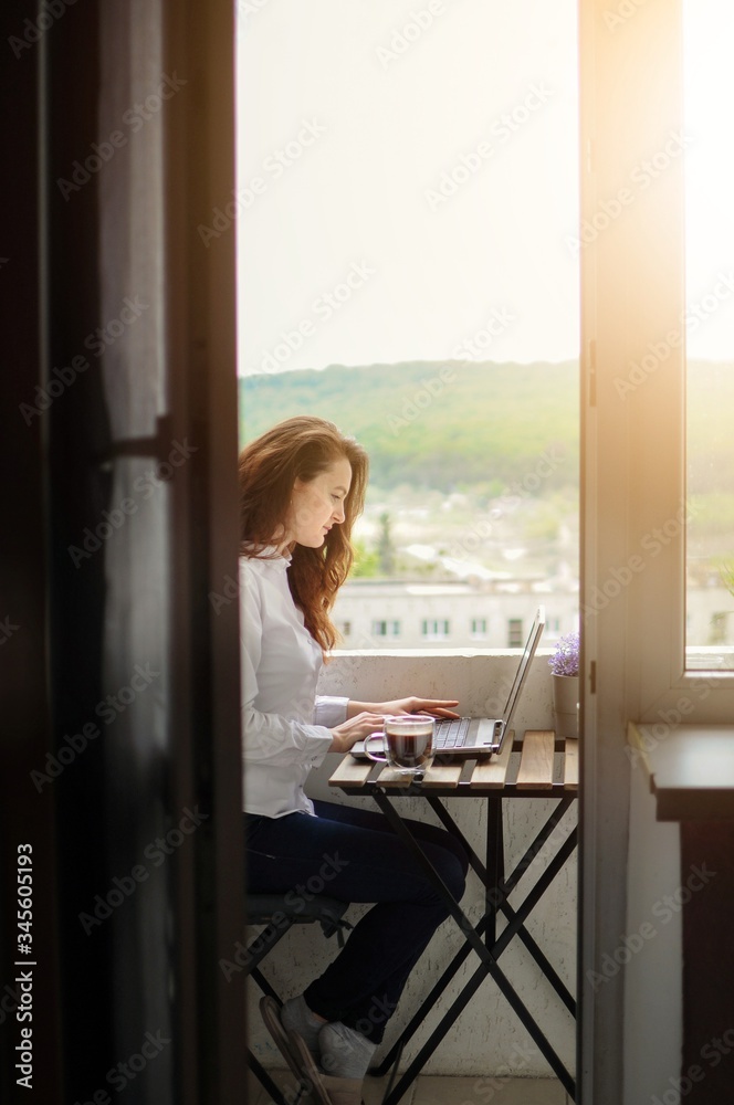 Woman freelancer working on a laptop on balcony during corona virus quarantine Woman freelancer working on a laptop on balcony during corona virus quarantine