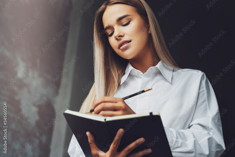 Student is preparing for seminar, writes notes in notebook. Beautiful woman holding notebook writes notes in pencil. Student is preparing for seminar, writes notes in notebook. Beautiful woman holding notebook writes notes in pencil.