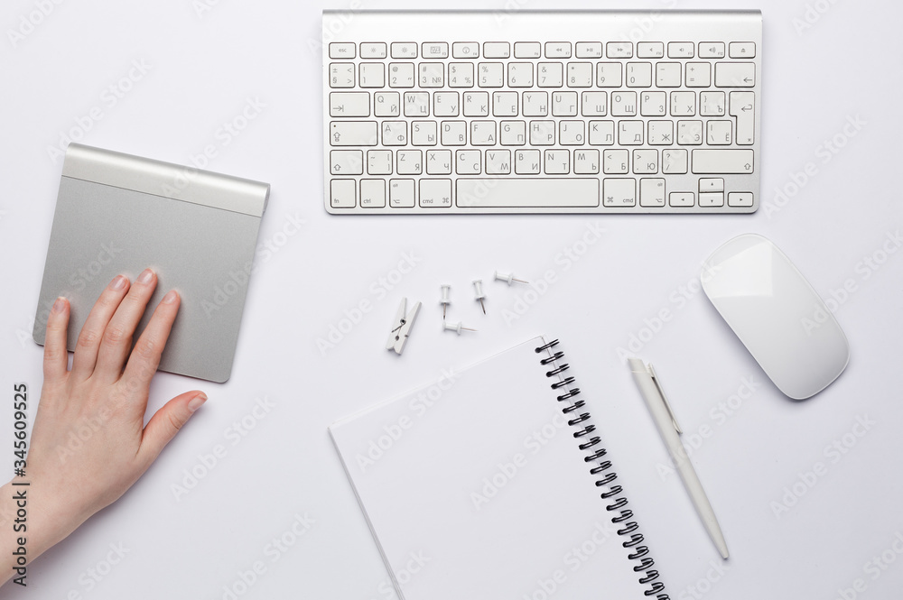 Keyboard with white blank notebook and touchpad with woman's hand on it. Keyboard with white blank notebook and touchpad with woman's hand on it.