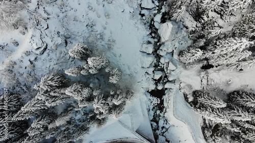 Aerial shot of snowy landscape with small rocky river 
