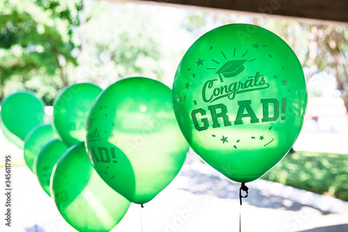 Close-up of Green Helium-filled graduation party balloons with Congrats Grad message in an outdoor setting