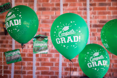 Green Graduation Party Balloons with Congrats Grad message in front of red brick wall with party decor in the background