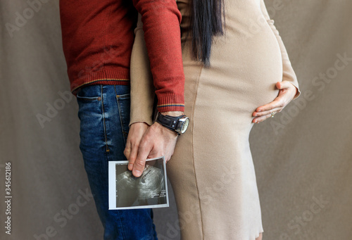 pregnant girl and guy hold ultrasound scan photo in hands
