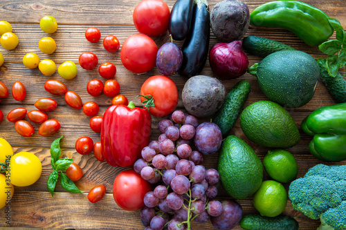 Colorful rainbow assortment of fresh fruits and vegetables on brown wooden rustic background