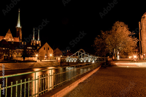 Wroclaw by night. View of cathedral, river, lovers bridge and Ostrow Tumski district. Historic architecture, gothic style. Lamps, flares, light. Cityscape shot in Poland.
