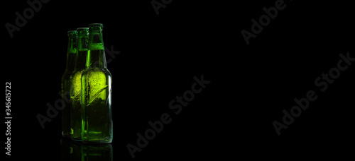 Green beer bottles on a black background on the side. Free space for text.