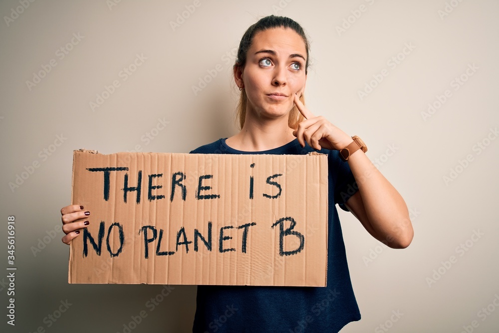 Young beautiful blonde woman with blue eyes asking for protect planet holding banner serious face thinking about question, very confused idea Young beautiful blonde woman with blue eyes asking for protect planet holding banner serious face thinking about question, very confused idea