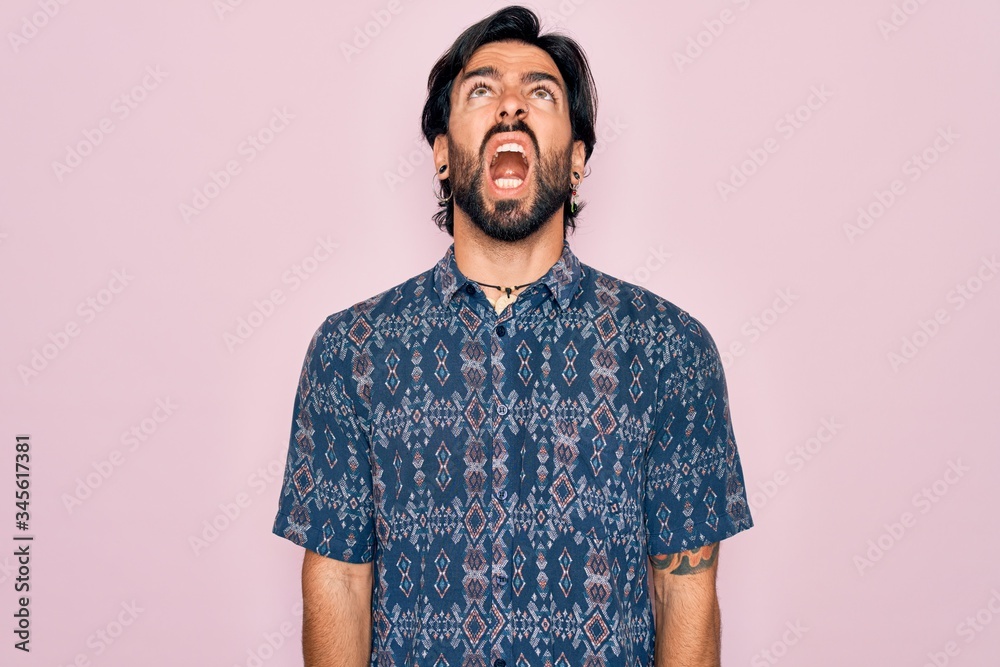 Young handsome hispanic bohemian man wearing hippie style over pink background angry and mad screaming frustrated and furious, shouting with anger. Rage and aggressive concept. Young handsome hispanic bohemian man wearing hippie style over pink background angry and mad screaming frustrated and furious, shouting with anger. Rage and aggressive concept.