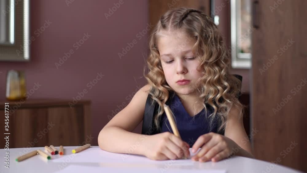 Portrait of cute curly girl thinking about what picture do drawing with colorful pencil at the table in cozy children's room. Concept of child creative activity. Shooting in slow motion. Portrait of cute curly girl thinking about what picture do drawing with colorful pencil at the table in cozy children's room. Concept of child creative activity. Shooting in slow motion.