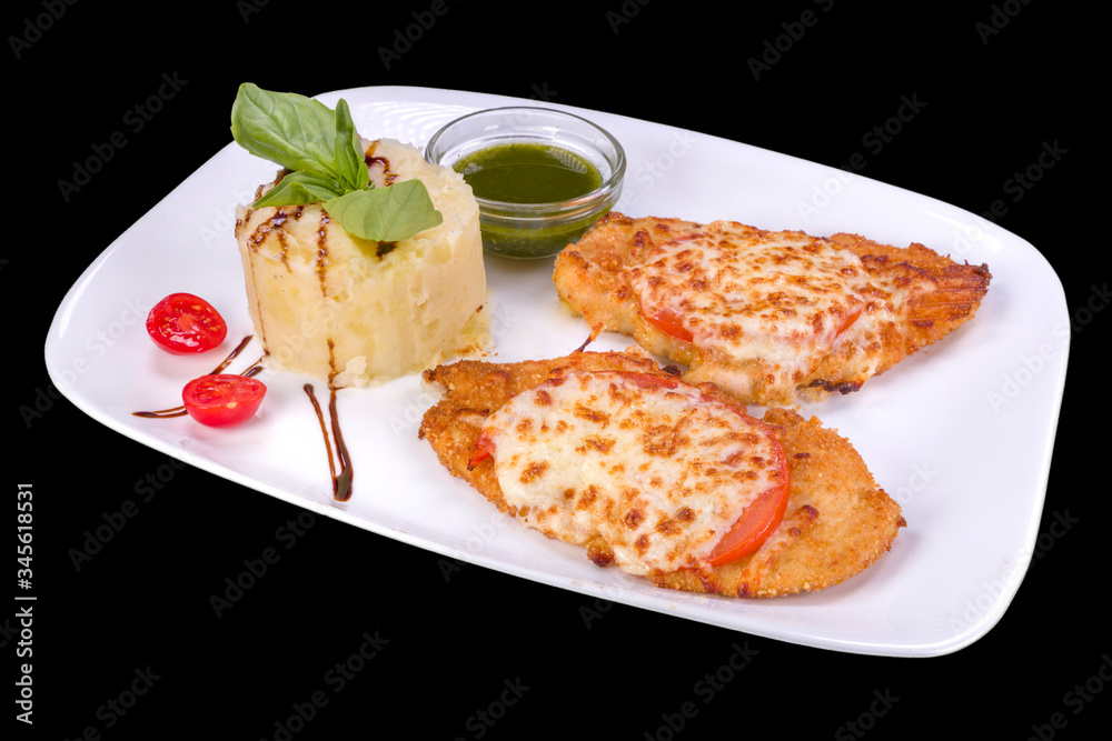 Tasty fried chicken with tomato and parmesan served with sauce and mashed potatoes, isolated on black background