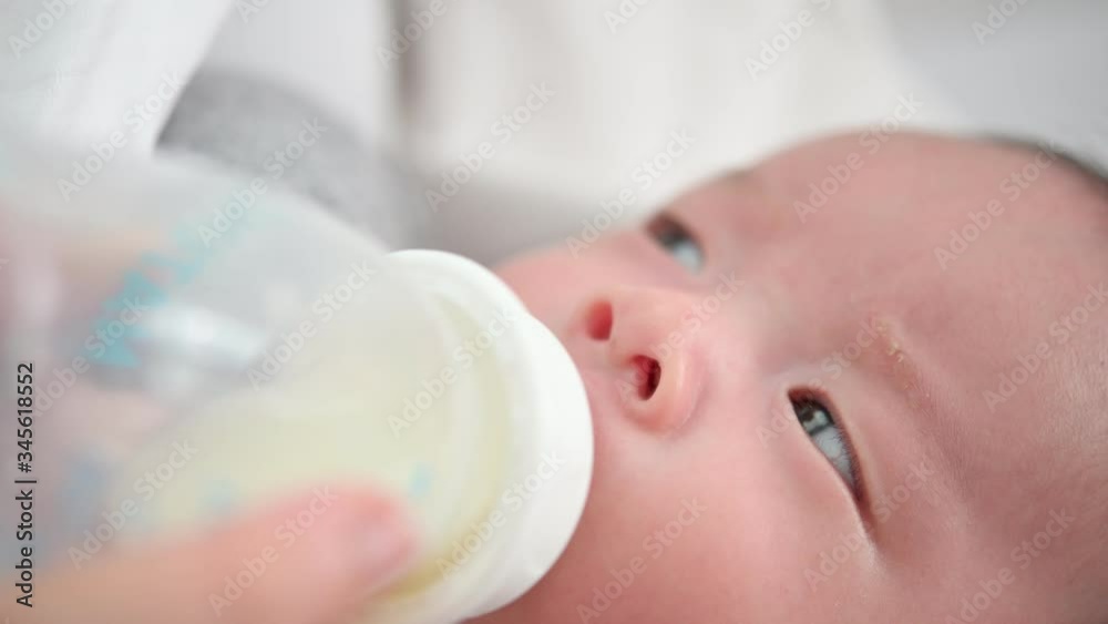 Mother feeding her adorable newborn baby kid's room at home.A woman feeds a newborn with modified milk from a bottle Mother feeding her adorable newborn baby kid's room at home.A woman feeds a newborn with modified milk from a bottle