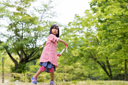 春の公園でシャボン玉を遊んでいる可愛い子供