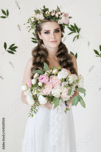 The bride holds a wedding bouquet, wedding dress, wedding details. wedding bouquet of peonies. Bride with snatural wreath of fresh flowers. Hairstyle from volumetric braids. lifestyle, fashion photo