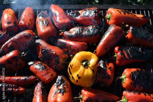 Red peppers grilling during outside outdoor BBQ or picnic. Man preparing vegetable barbecue