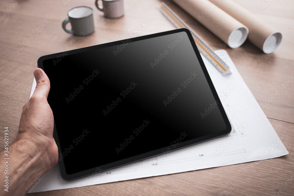 Tablette tenue en main par un architecte travaillant sur un projet de construction d'une maison ou d'un projet industriel Tablette tenue en main par un architecte travaillant sur un projet de construction d'une maison ou d'un projet industriel