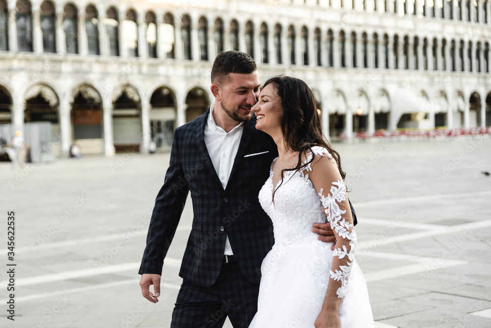 Naklejka premium happy bride and groom cuddle during a wedding walk,lovely couple's wedding day,beautiful outfits of the newlyweds,