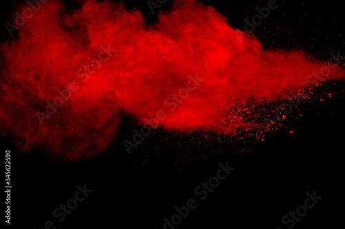 Red particles explosion on black background. Freeze motion of red dust splash.