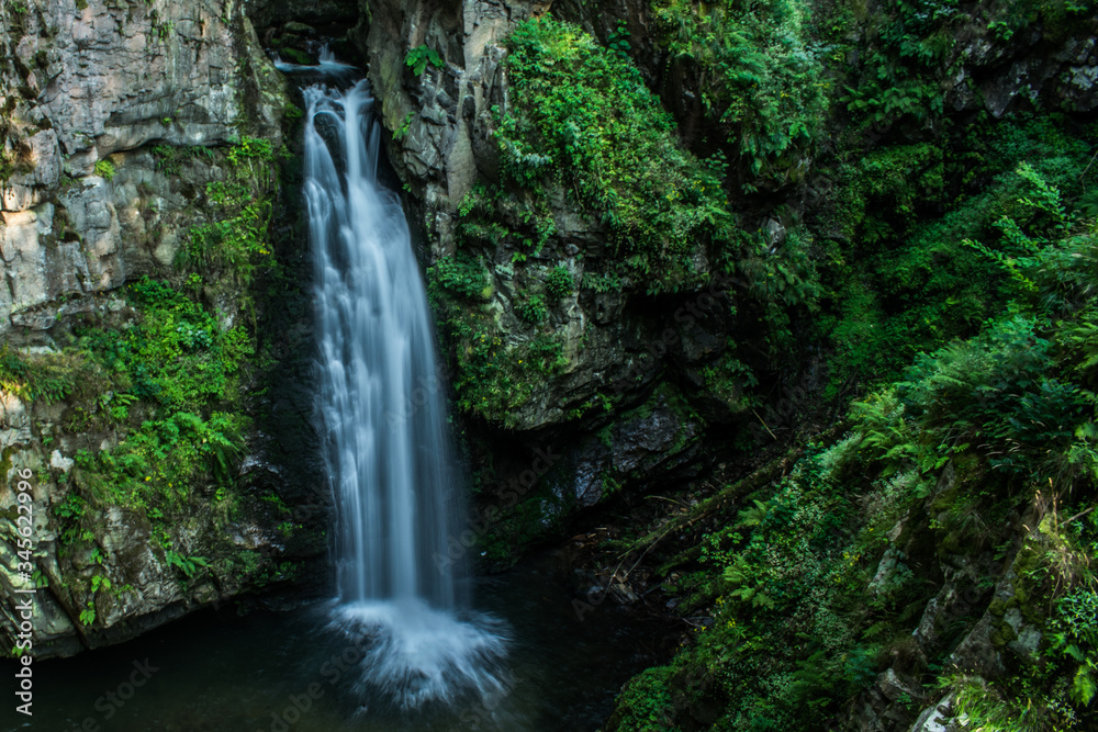 Blurred mountain waterfall in the forest. Landscape of Miedzygorze, Sudety, Poland.