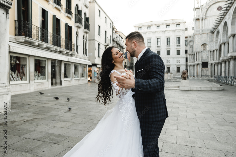Naklejka premium bride and groom on the background of a historic building,bride and groom walk the streets of the old city of venice,newlyweds dance,european wedding,quarantine wedding