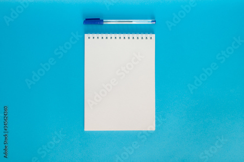 Open notebook with a pen on blue background