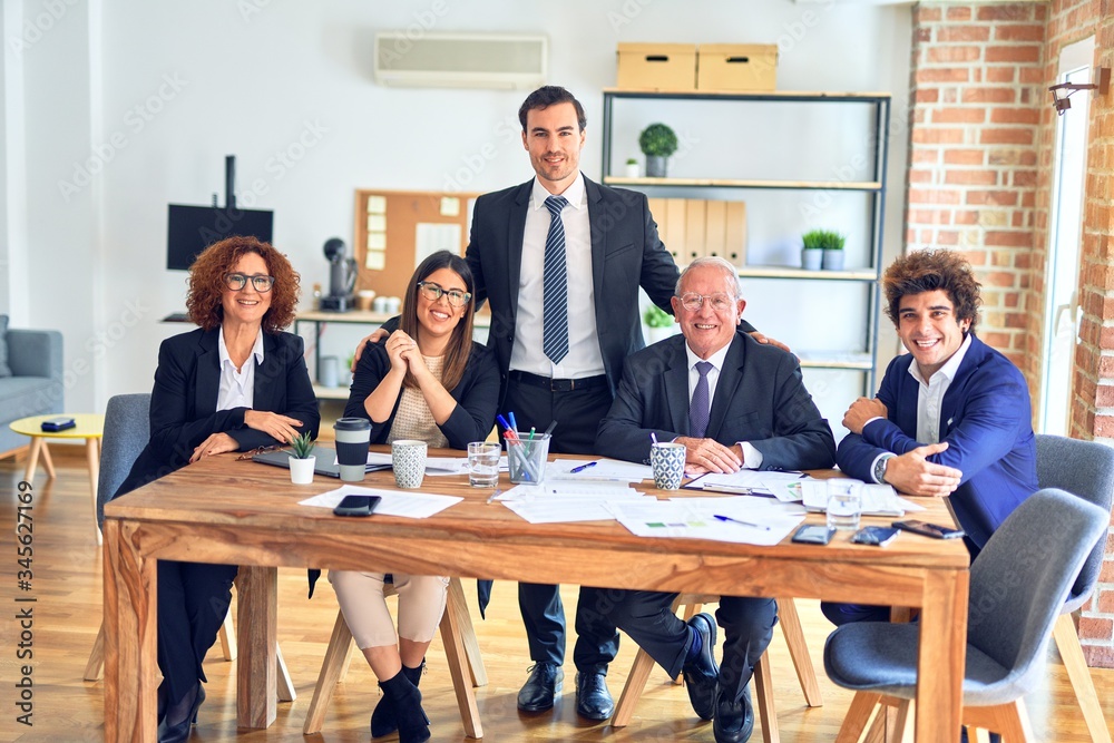 Group of business workers smiling happy and confident in a meeting. The boss standing and employees sitting with smile on face looking at the camera at the office Group of business workers smiling happy and confident in a meeting. The boss standing and employees sitting with smile on face looking at the camera at the office
