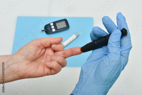 Close up of woman hands using black lancet on finger to check blood sugar level 