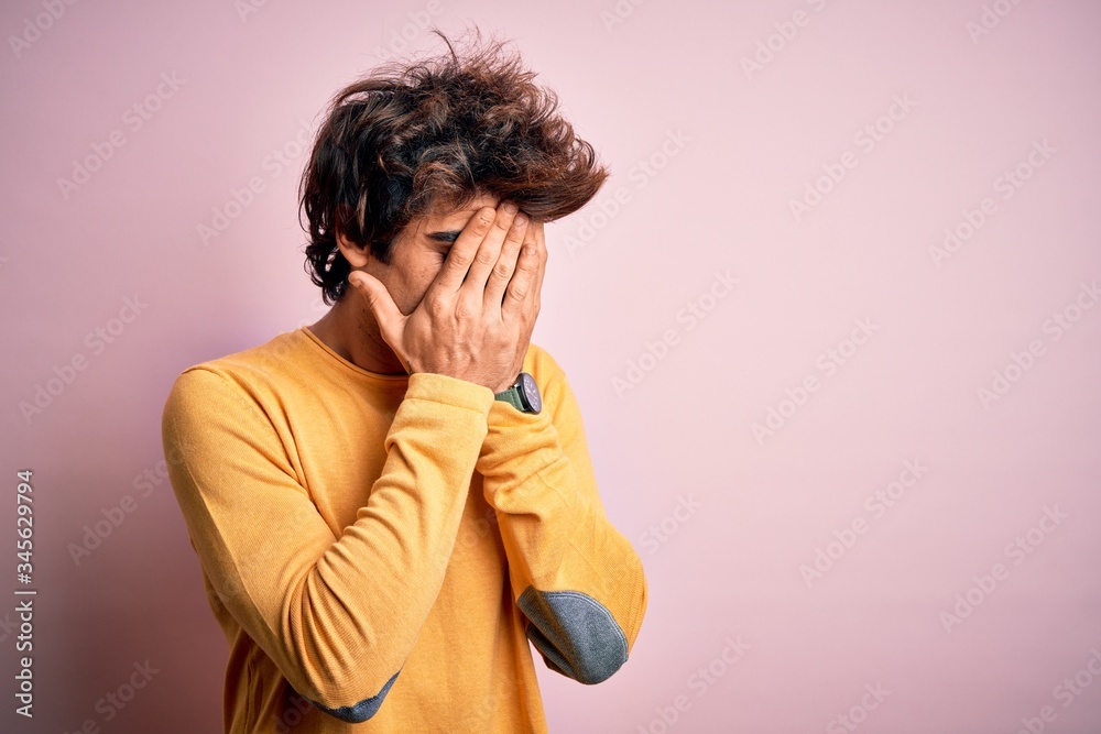 Young handsome man wearing yellow casual t-shirt standing over isolated pink background with sad expression covering face with hands while crying. Depression concept. Young handsome man wearing yellow casual t-shirt standing over isolated pink background with sad expression covering face with hands while crying. Depression concept.