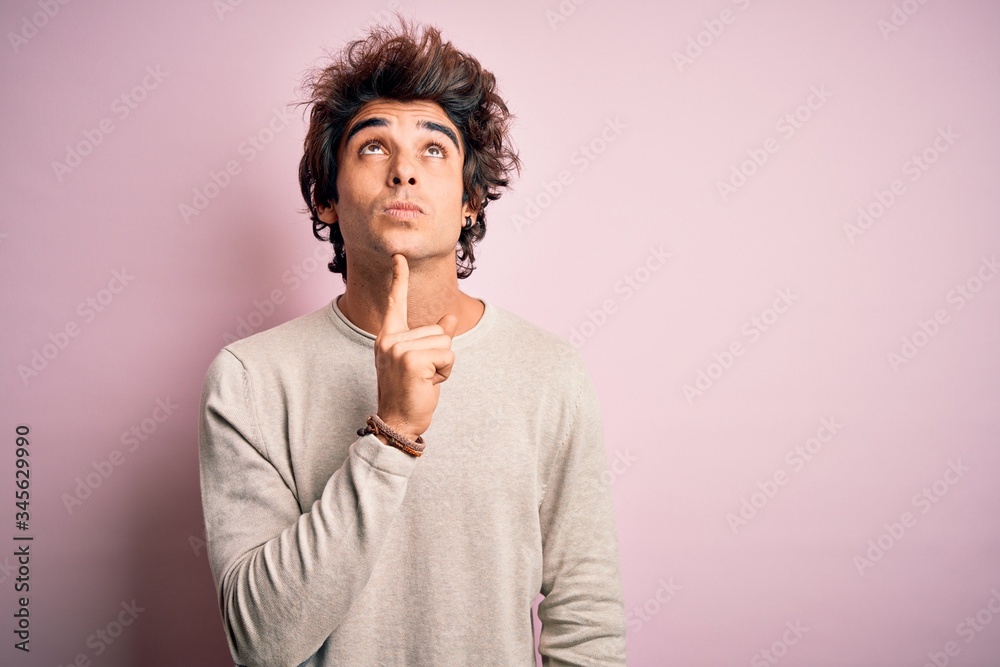 Young handsome man wearing casual t-shirt standing over isolated pink background Thinking concentrated about doubt with finger on chin and looking up wondering Young handsome man wearing casual t-shirt standing over isolated pink background Thinking concentrated about doubt with finger on chin and looking up wondering