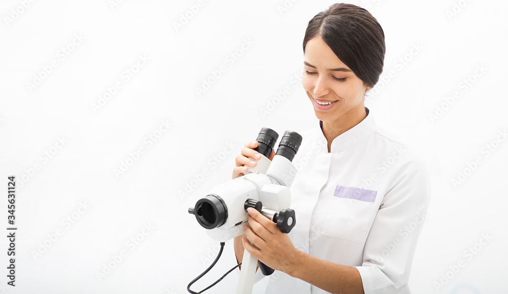 Portrait of a mixed race gynecologist sitting in an office near a colposcope. Gynecologist profession Portrait of a mixed race gynecologist sitting in an office near a colposcope. Gynecologist profession