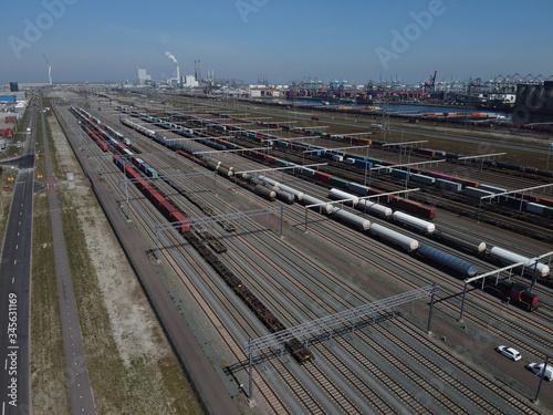 Aerial bird view photo of railroad container terminal with train loaded with containers by overhead crane also showing classification yard and heavy industry