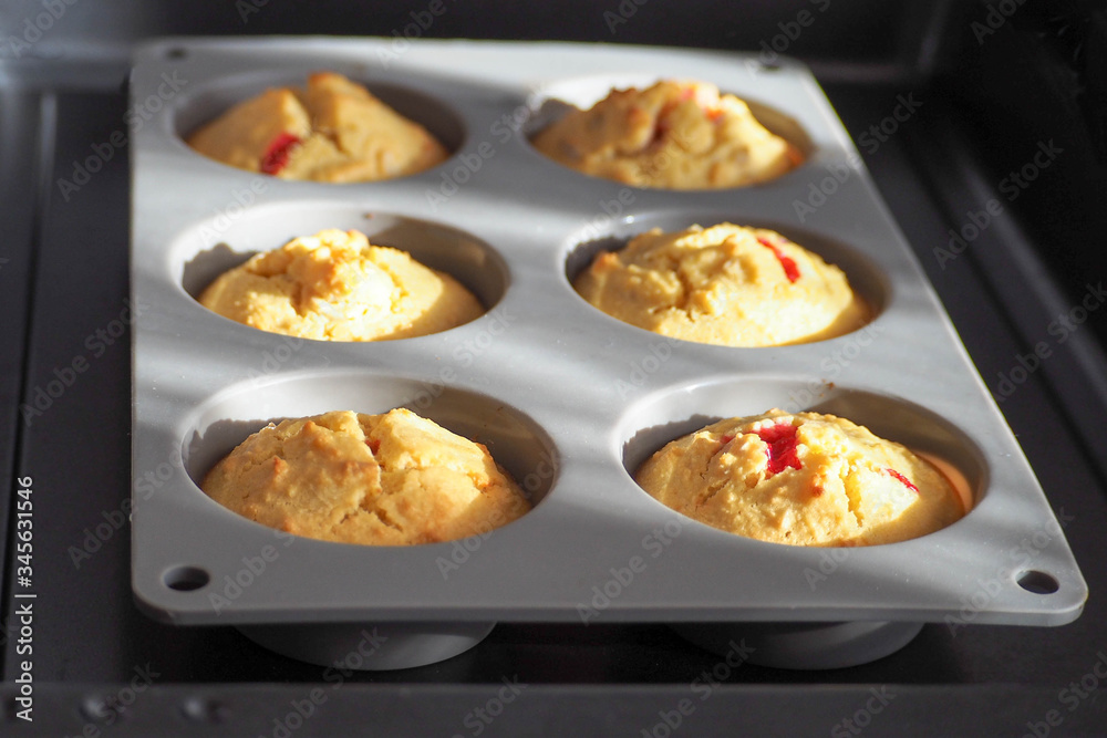 gluten-free muffins with red currant are prepared from the oven . . gray silicone mold for six pieces on a dark metal protwin gluten-free muffins with red currant are prepared from the oven . . gray silicone mold for six pieces on a dark metal protwin