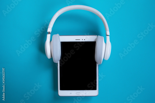 white headphones put on a white tablet on a blue background