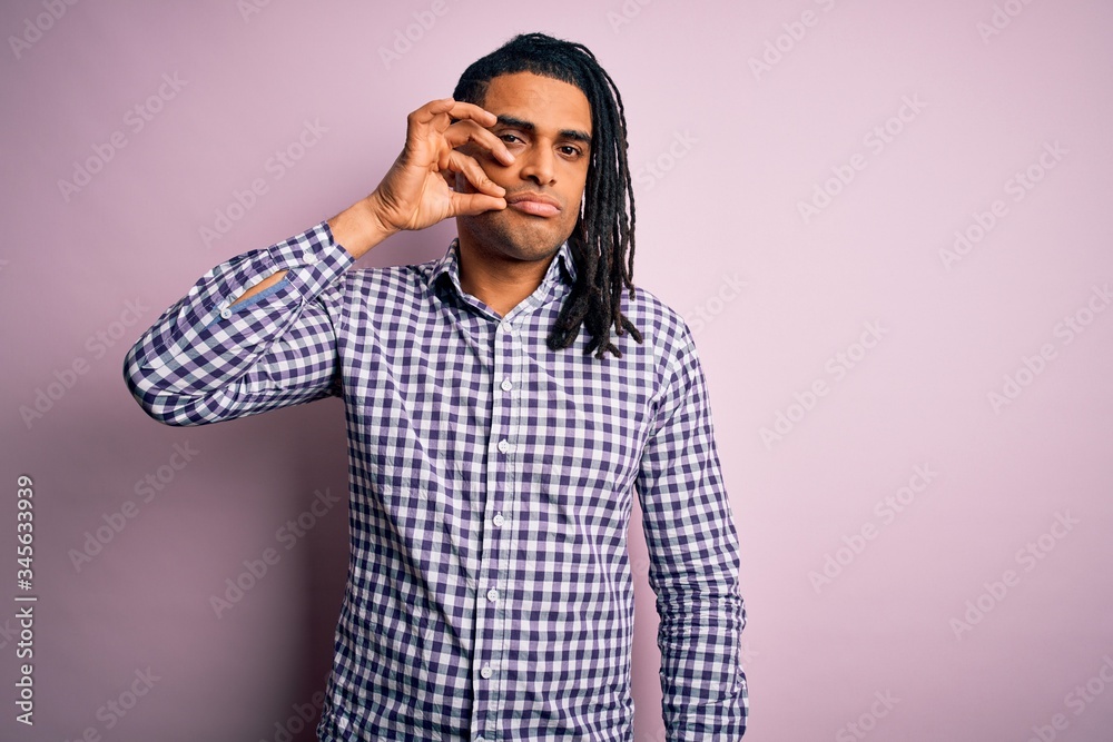 Young handsome african american afro man with dreadlocks wearing casual shirt mouth and lips shut as zip with fingers. Secret and silent, taboo talking