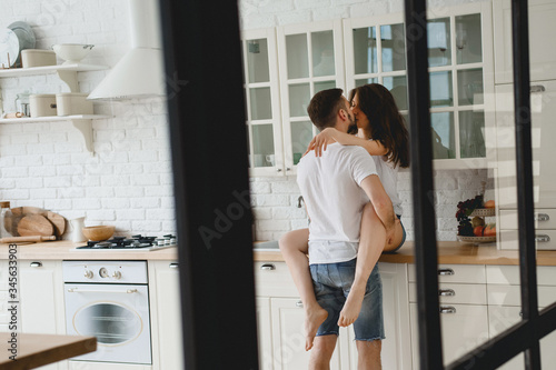 The guy passionately kisses the girl sitting on the kitchen table