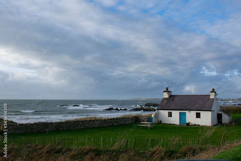 A remote isolated, traditional, country cottage by a windswept beach on a winters day.  A view out to the Irish sea from the Welsh island of Anglesey