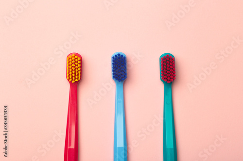 Toothbrushes of different colors on a pink background. Brushing teeth and oral hygiene.