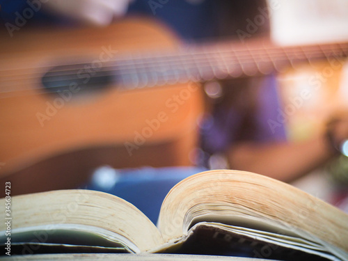 The book of songs behind the woman has strumed on the guitar
