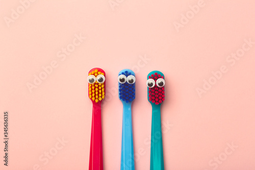 Kids toothbrushes of different colors on a pink background. Teeth and oral hygiene for children