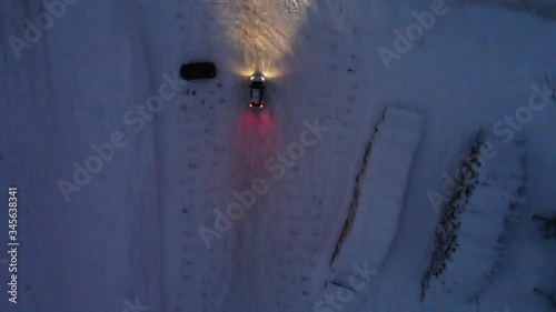 Aerial footage of car driving around on snow covered parking 