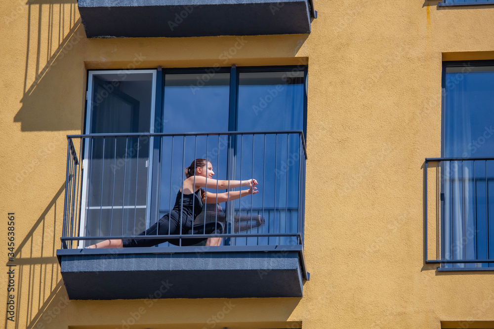 woman practices sport on balcony of the apartment. Stay home during an epidemic
