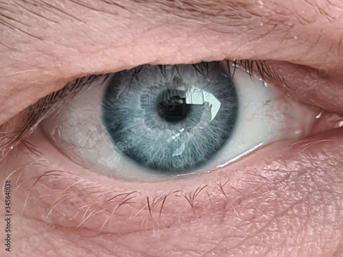 Close-up of mature mans blue eye ball. Middle-aged males face with wrinkles. Detailed picture of person. Eyebrow and eyelash. Ageing millennial skin concept