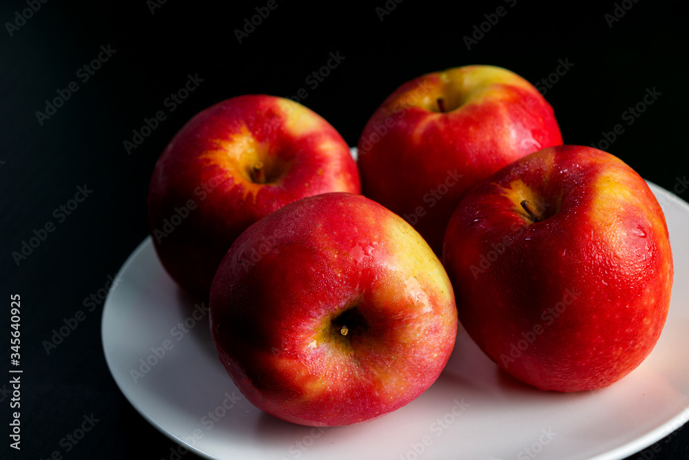 Apples, red, yellow, four fruits, white plates, black wood flooring, green walls Apples, red, yellow, four fruits, white plates, black wood flooring, green walls