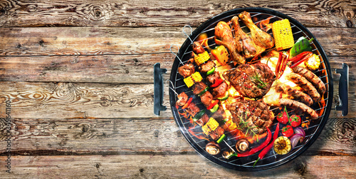 Top view of assorted delicious grilled meat with vegetables on barbecue on rustic wooden planks