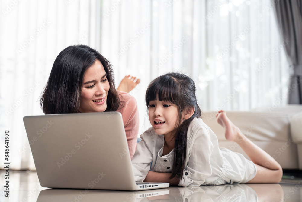 Homeschool Asian little young girl feel relax, learning internet online class by using computer with mother help, teach laying on floor. Daughter smile and happy to study at home together with mom. Homeschool Asian little young girl feel relax, learning internet online class by using computer with mother help, teach laying on floor. Daughter smile and happy to study at home together with mom.